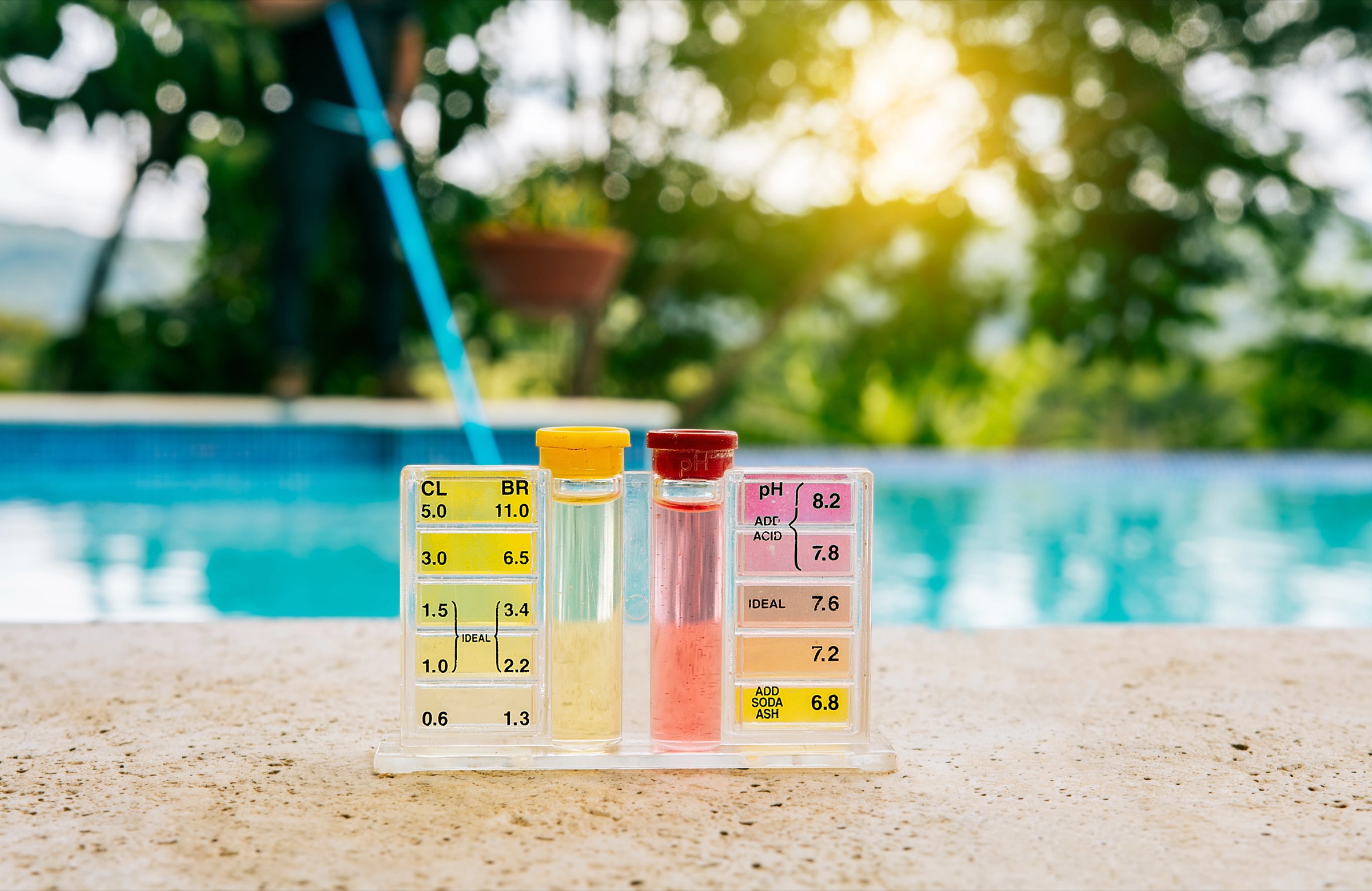 Tester kit to measure chlorine and ph in swimming pools. Pool water PH tester kit on the edge of the swimming pool Tester kit to measure chlorine and ph in swimming pools. Pool water PH tester kit on the edge of the swimming pool